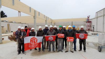 Bauarbeiter in einem Hallen-Rohbau, mit IG BAU-Flaggen Bauarbeiter in einem Hallen-Rohbau, mit IG BAU-Flaggen