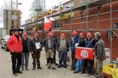 Bauleute mit IG BAU-Fahnen vor einem Rohbau mit Verblend-Arbeiten Bauleute mit IG BAU-Fahnen vor einem Rohbau mit Verblend-Arbeiten