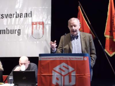 Klaus Knickmeier am Rednerpult, davor eine IG BAU-Fahne