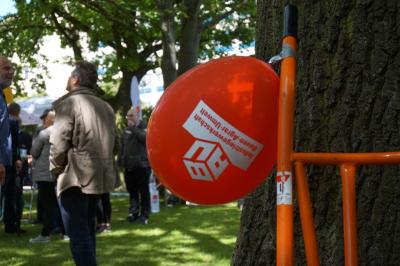 Luftballon mit IG BAU-Aufdruck, im Hintergrund mehrere Personen, die sich unterhalten