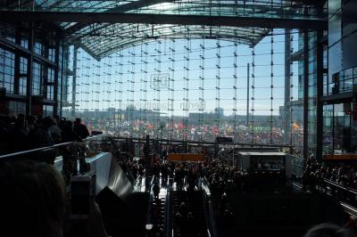 Große Glasfassade, darauf der Schriftzug &quot;Berlin Hauptbahnhof&quot; von hinten, dahinter Zehntausende Menschen mit Fahnen.