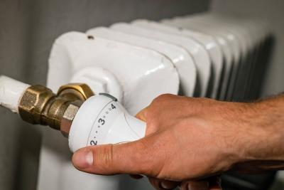 Eine Hand dreht an einem Heizungsthermostat. Eine Hand dreht an einem Heizungsthermostat.