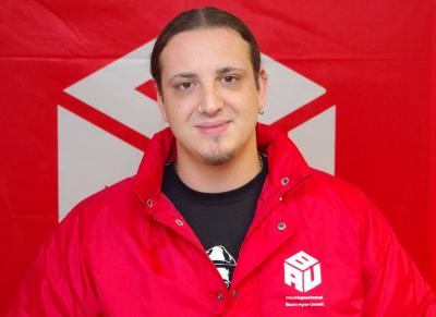 Harry Gosch in roter BAU-Jacke vor einer roten BAU-Fahne