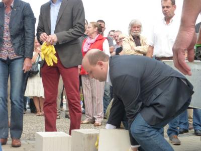 Manuel Sarrazin (Grüne) hebt einen Kalksandstein-Block aufs vorbereitete Mauerwerk.