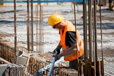 Bauarbeiter mit Warnweste zwischen Bewehrungsstählen auf einem Neubau. Bauarbeiter mit Warnweste zwischen Bewehrungsstählen auf einem Neubau.