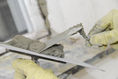 Nahaufnahme: Mörtel wird mit einer Vierkant-Kelle von einem Glätter genommen. Nahaufnahme: Mörtel wird mit einer Vierkant-Kelle von einem Glätter genommen.