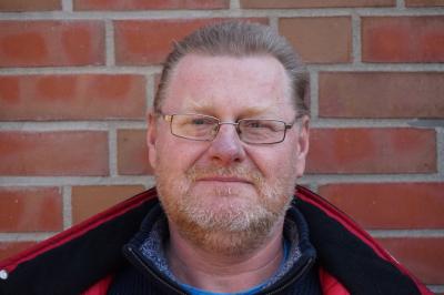 Portraitaufnahme Helge Gutt vor einer gemauerten Wand