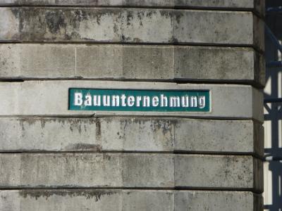 Schriftzug "Bauunternehmung" in weiß auf grünem Untergrund - das ganze auf einem von mehreren aufeinander gestapelten Betonplatten. Schriftzug "Bauunternehmung" in weiß auf grünem Untergrund - das ganze auf einem von mehreren aufeinander gestapelten Betonplatten.